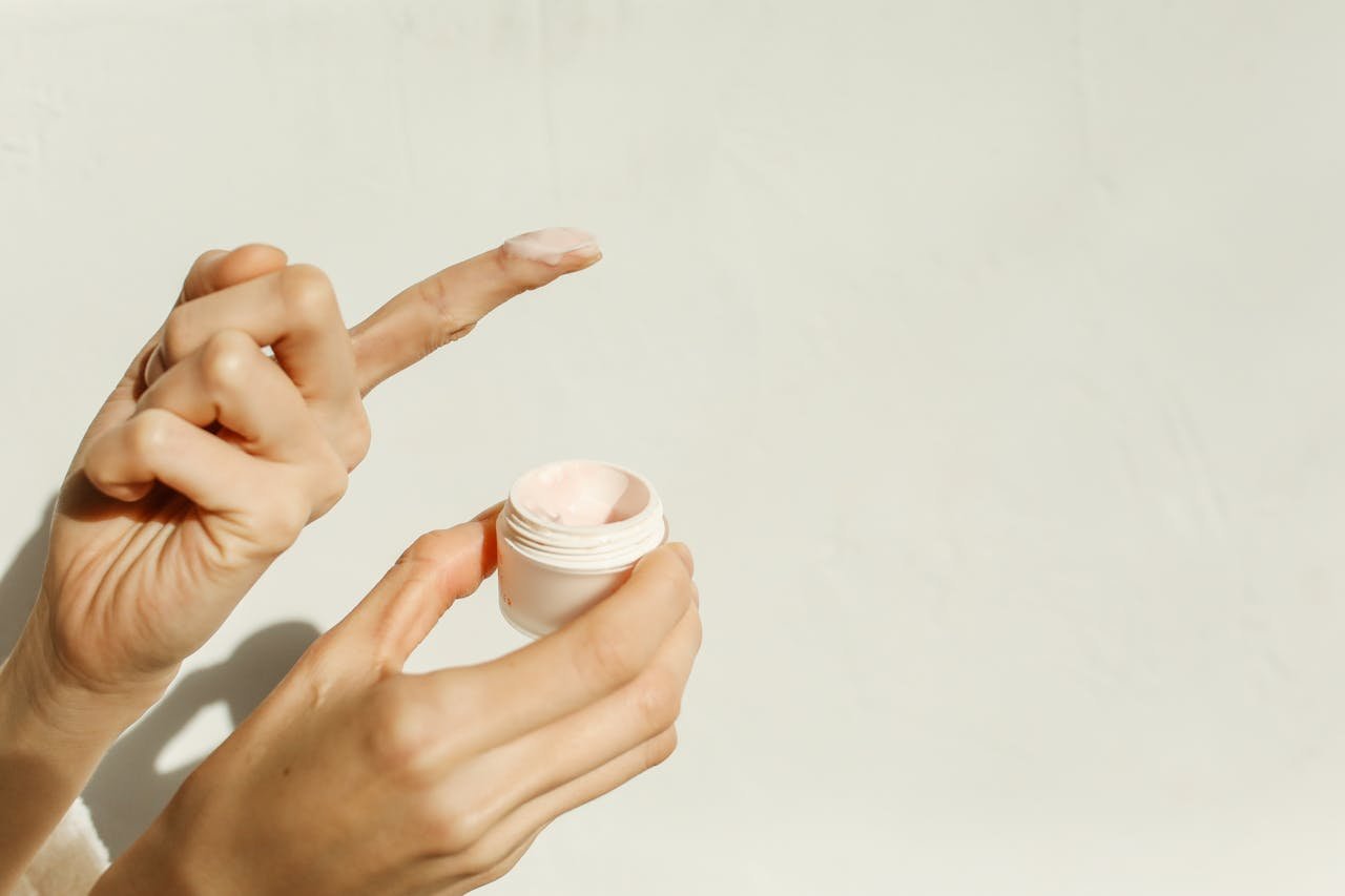 hero-img-01 A close-up image showing hands applying facial cream, reflecting a minimalist skincare routine.
