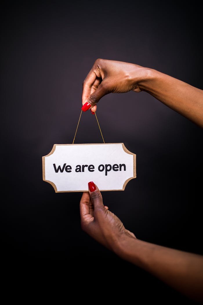 why-choose-us Close-up of hands holding an 'Open' sign with a black background, perfect for business promotions.
